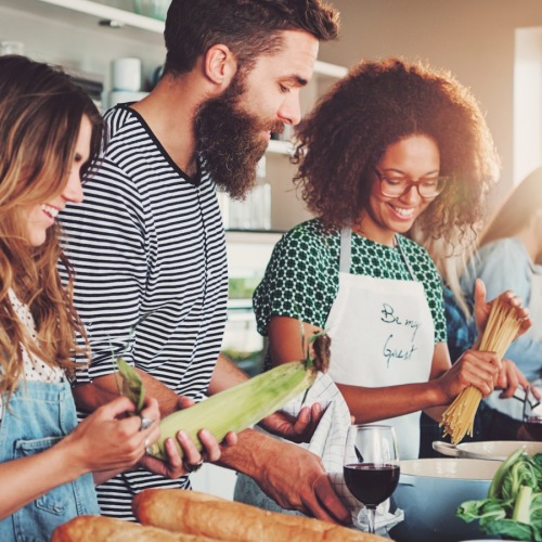 a group of people standing around a table with food and drinks
